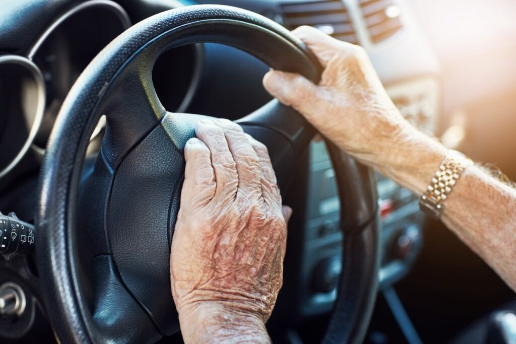 Senior mans hands on the steering wheel of his car